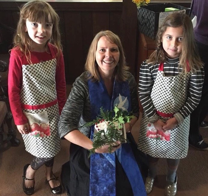 IMAGE: Reverend Tera holding a floral arrangement, with two girls.